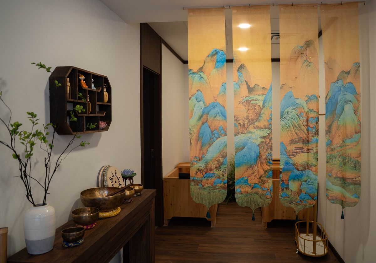 Singing bowls on a wooden console beside the painted scrolls of the meditation room at Healing Lotus Skin Spa